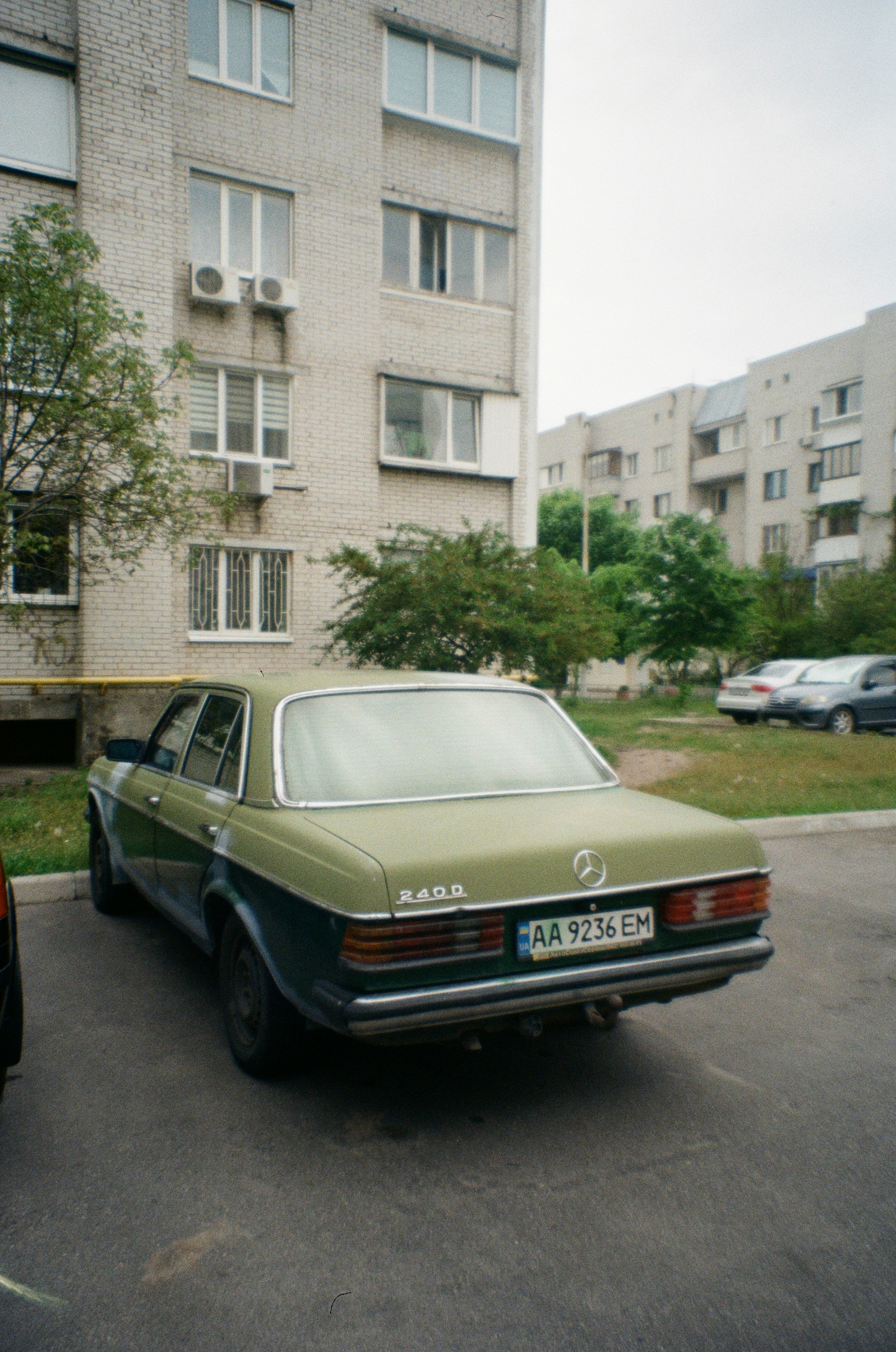 black mercedes benz sedan parked beside white concrete building during daytime